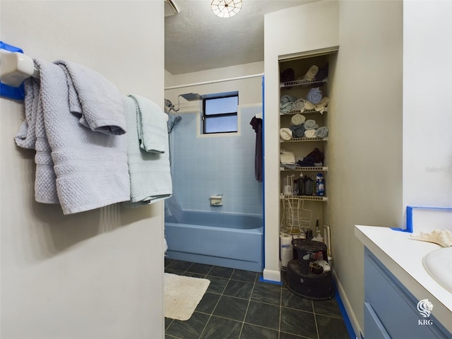 bathroom with tile patterned floors, a textured ceiling, tiled shower / bath combo, and vanity