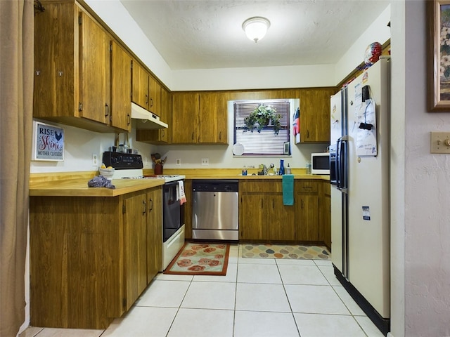 kitchen featuring sink, light tile patterned floors, white appliances, and kitchen peninsula