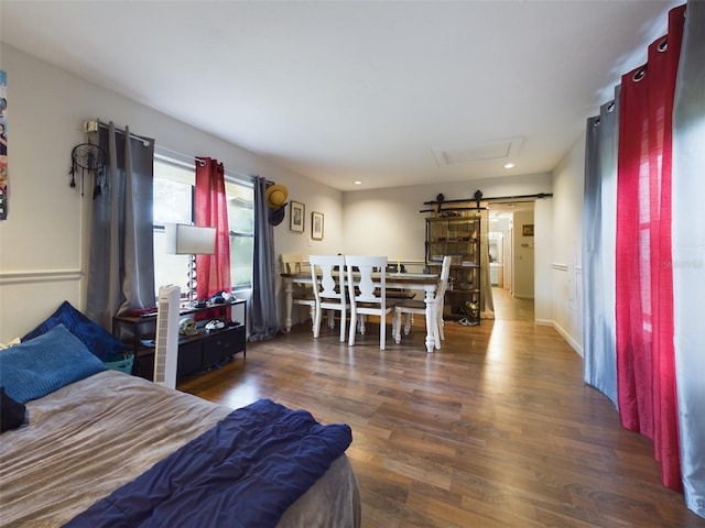 bedroom with a barn door and dark hardwood / wood-style floors