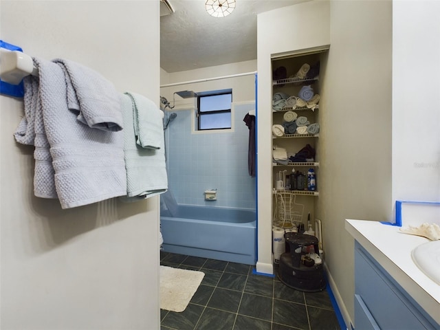 bathroom with tile patterned floors, vanity, tiled shower / bath combo, and a textured ceiling