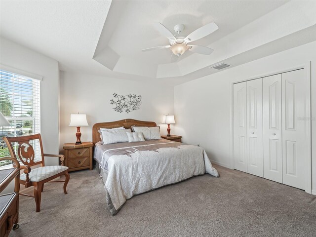 bedroom featuring ceiling fan, a closet, a raised ceiling, and carpet flooring