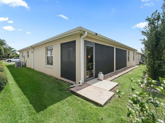 rear view of house featuring a lawn and central air condition unit