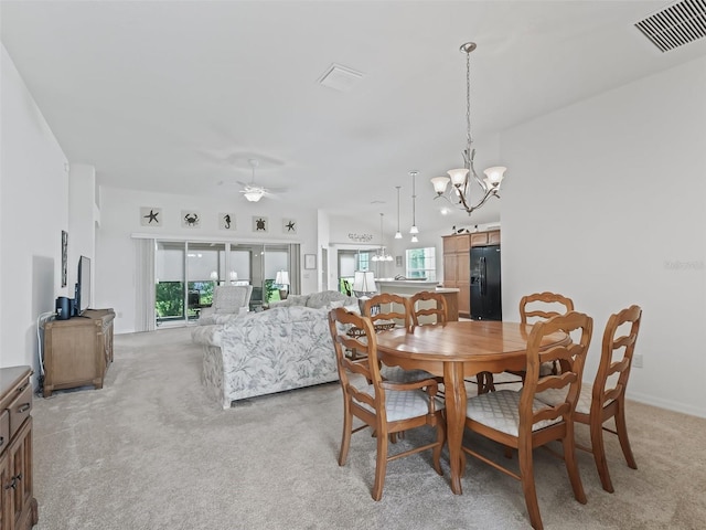 dining space with light colored carpet, ceiling fan with notable chandelier, and a wealth of natural light