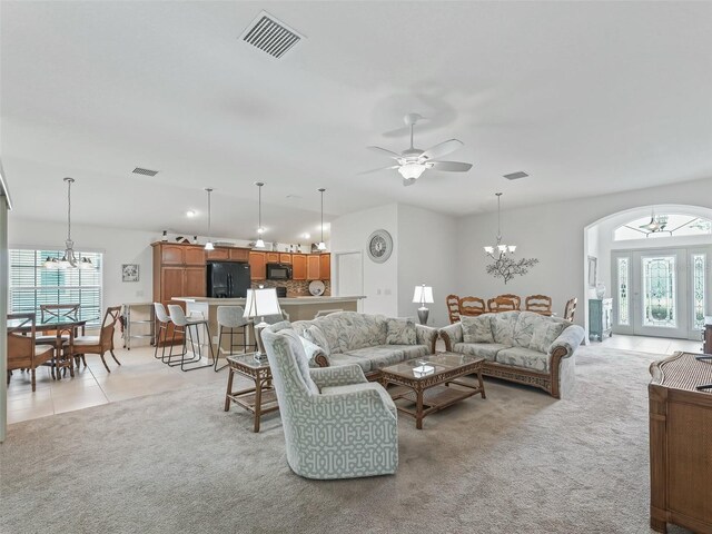 carpeted living room featuring ceiling fan with notable chandelier