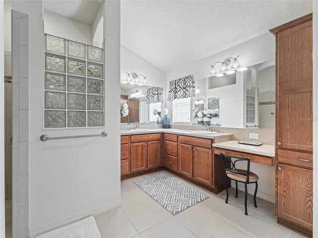 bathroom featuring vanity, lofted ceiling, tile patterned flooring, and a textured ceiling