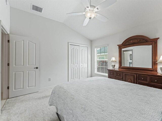 bedroom featuring ceiling fan, light colored carpet, lofted ceiling, and a closet