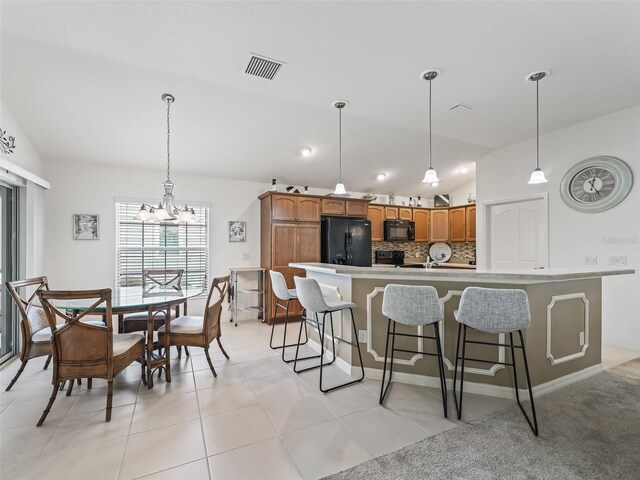 kitchen with an inviting chandelier, black appliances, vaulted ceiling, and light tile patterned floors