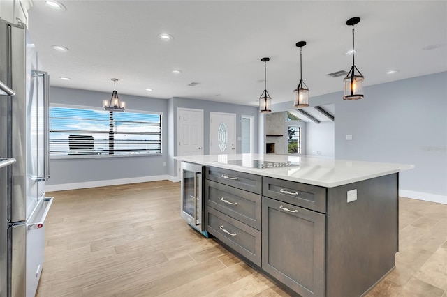 kitchen with a healthy amount of sunlight, a kitchen island, beverage cooler, and decorative light fixtures