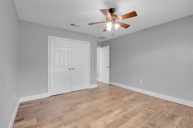 unfurnished bedroom featuring light hardwood / wood-style floors, ceiling fan, and a closet