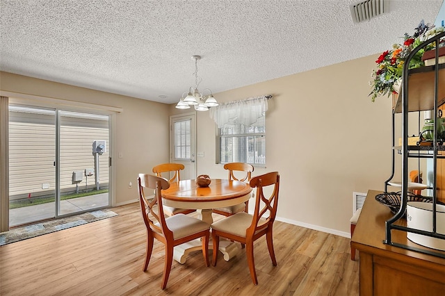 dining room with light wood-type flooring, a chandelier, and a textured ceiling