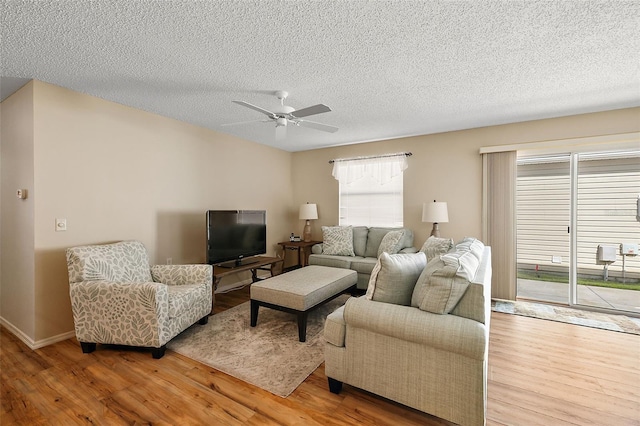 living room with a textured ceiling, ceiling fan, and hardwood / wood-style flooring