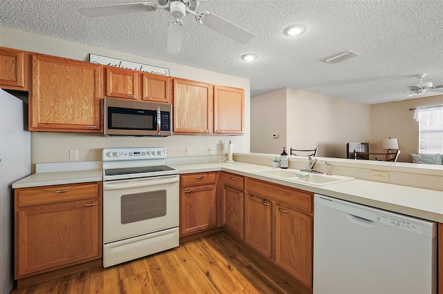 kitchen featuring ceiling fan, a textured ceiling, light wood-type flooring, and white appliances