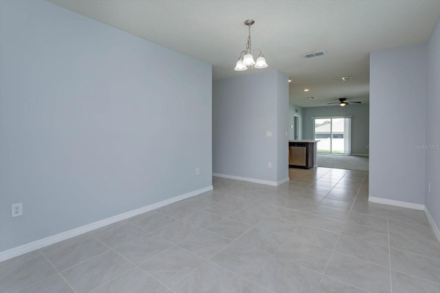 empty room featuring ceiling fan with notable chandelier and light tile patterned floors