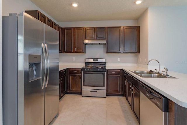 kitchen with light tile patterned floors, sink, kitchen peninsula, a textured ceiling, and stainless steel appliances