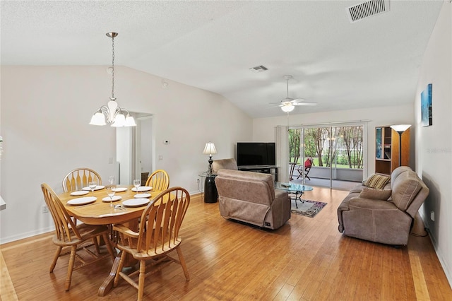 dining area featuring vaulted ceiling, ceiling fan with notable chandelier, and light hardwood / wood-style flooring