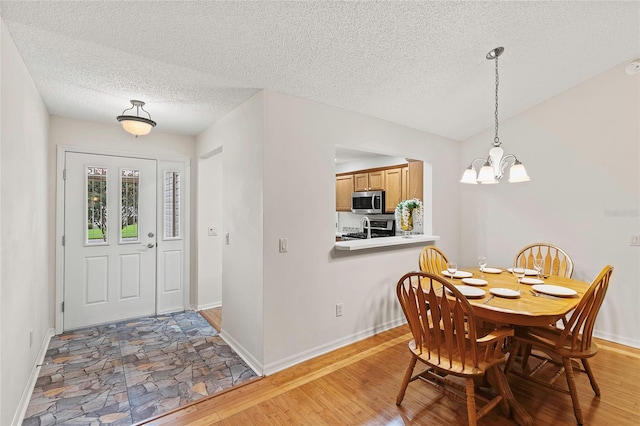 dining area with wood-type flooring, a notable chandelier, and a textured ceiling