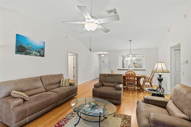 living room featuring light wood-type flooring, ceiling fan with notable chandelier, and lofted ceiling