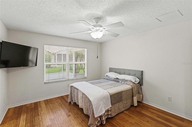 bedroom with a textured ceiling, hardwood / wood-style flooring, and ceiling fan