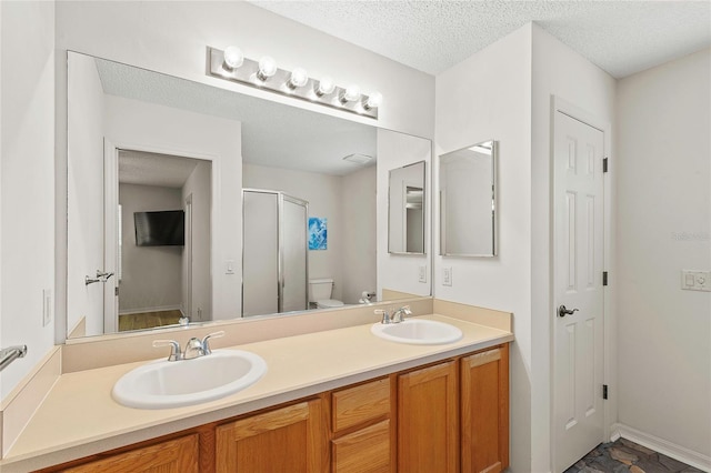 bathroom featuring an enclosed shower, vanity, a textured ceiling, and toilet