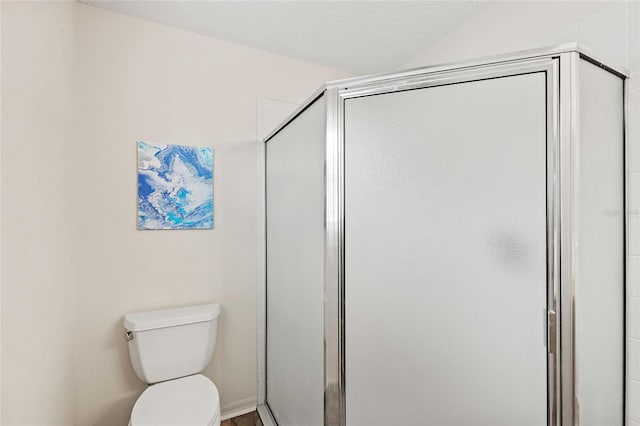 bathroom featuring a textured ceiling, toilet, and a shower with door