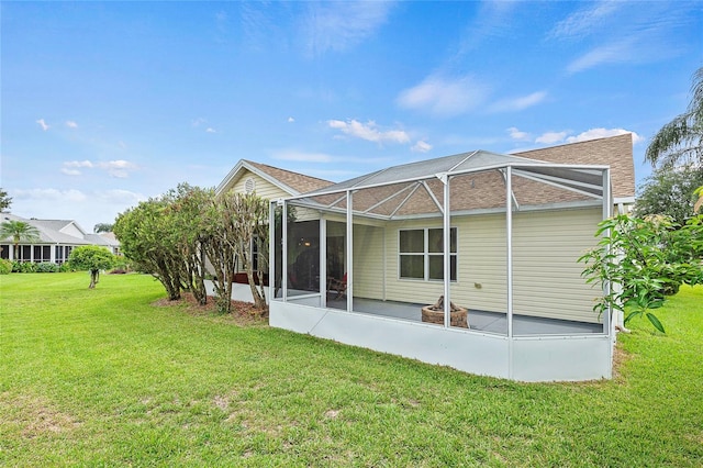 rear view of house featuring glass enclosure, a lawn, and a patio area