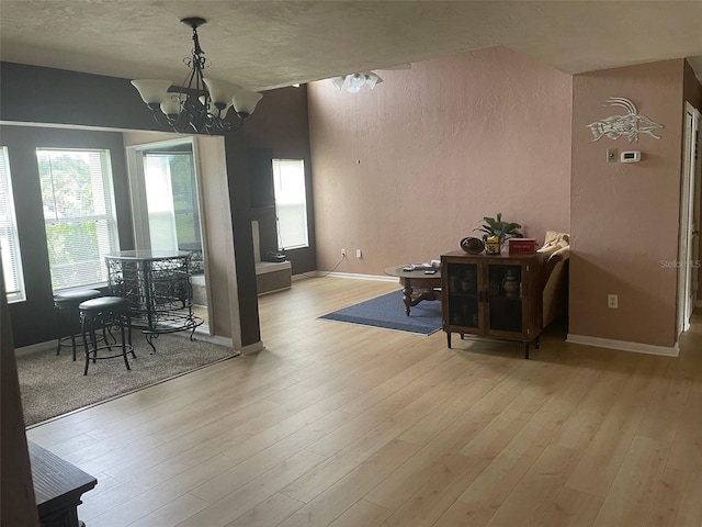 dining area featuring light hardwood / wood-style flooring, a textured ceiling, and an inviting chandelier