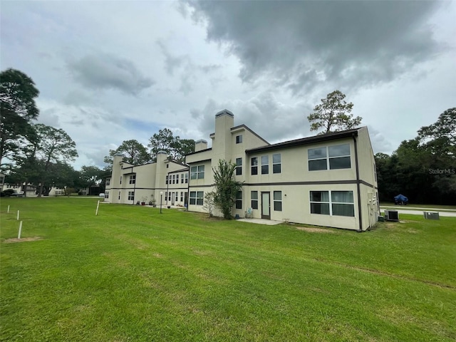 rear view of house featuring central AC and a yard