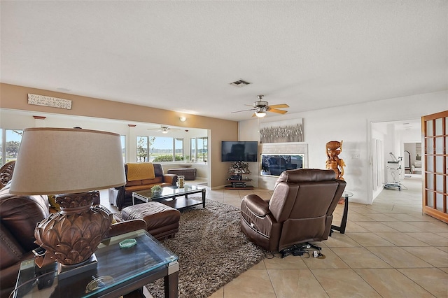 tiled living room with ceiling fan, a healthy amount of sunlight, and a textured ceiling