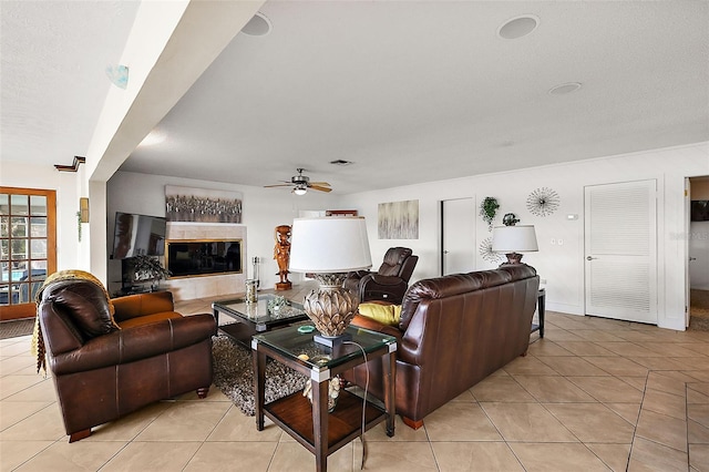 living room featuring a tile fireplace, ceiling fan, and light tile patterned floors