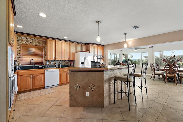 kitchen with a kitchen bar, appliances with stainless steel finishes, ceiling fan, sink, and decorative light fixtures