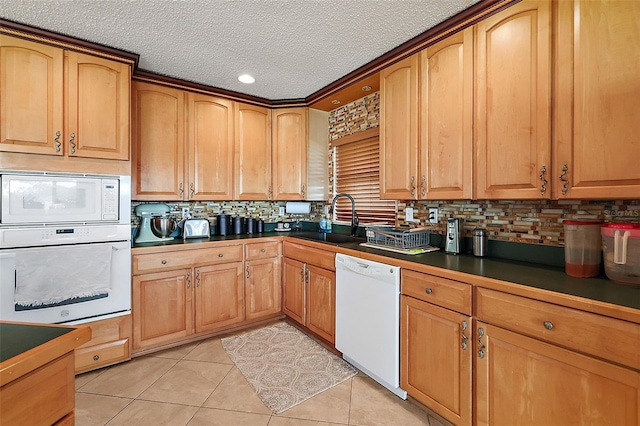 kitchen featuring decorative backsplash, light tile patterned floors, white appliances, and sink