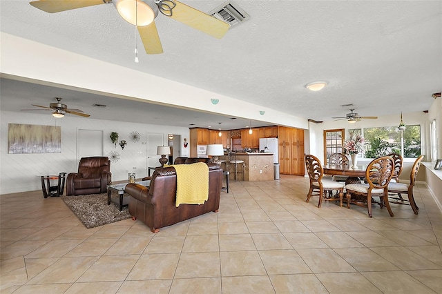 tiled living room with a textured ceiling and ceiling fan