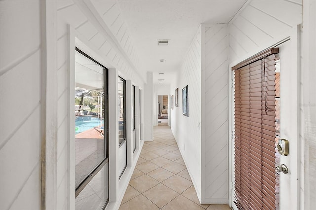 hall featuring light tile patterned flooring and wooden walls