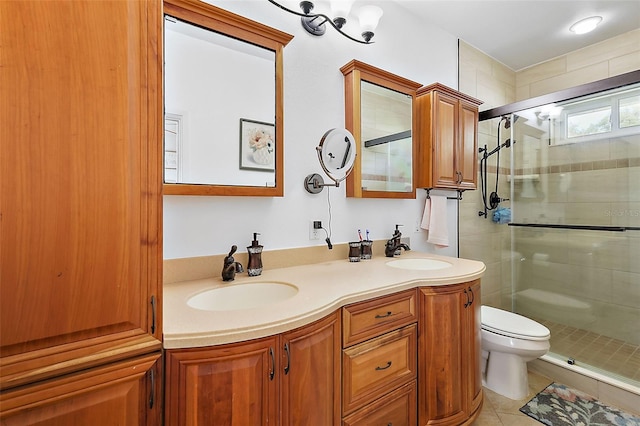 bathroom featuring tile patterned floors, vanity, a shower with shower door, and toilet