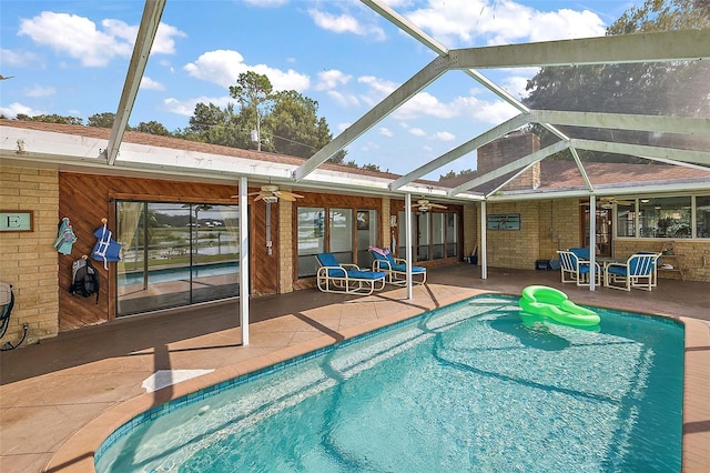 view of swimming pool with a patio, glass enclosure, and ceiling fan