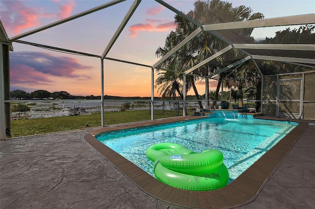 pool at dusk with glass enclosure, pool water feature, and a patio area