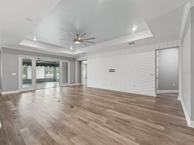 unfurnished living room featuring ceiling fan, hardwood / wood-style flooring, and a tray ceiling