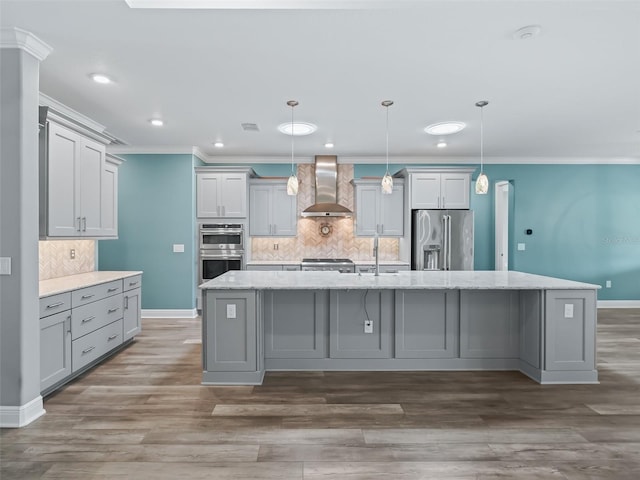 kitchen featuring hanging light fixtures, a kitchen island with sink, wall chimney range hood, stainless steel appliances, and dark hardwood / wood-style floors