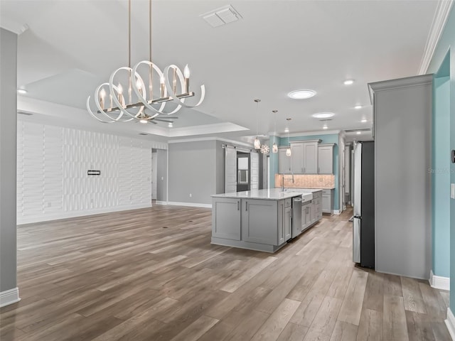 kitchen with a kitchen island, pendant lighting, stainless steel appliances, light hardwood / wood-style flooring, and a notable chandelier