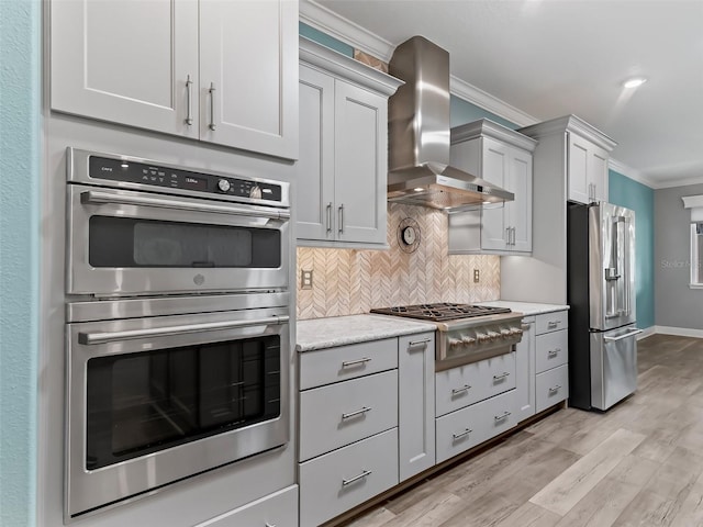 kitchen featuring appliances with stainless steel finishes, light wood-type flooring, ornamental molding, and wall chimney range hood