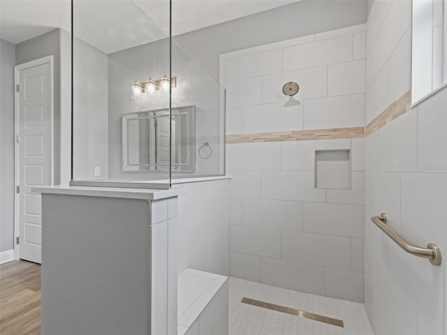 bathroom with hardwood / wood-style floors and a tile shower