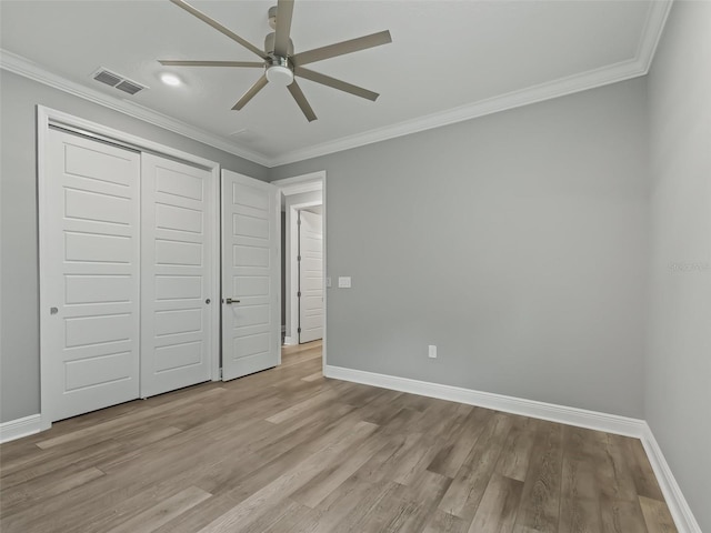 unfurnished bedroom featuring light wood-type flooring, ornamental molding, ceiling fan, and a closet