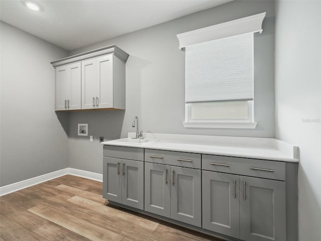 laundry room featuring washer hookup, sink, light hardwood / wood-style flooring, cabinets, and electric dryer hookup