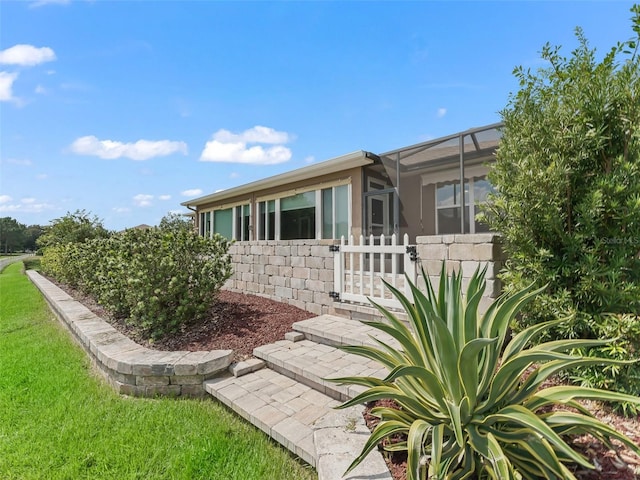 back of property featuring glass enclosure and a yard