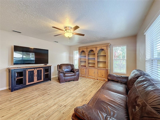 living room featuring light hardwood / wood-style flooring, ceiling fan, a healthy amount of sunlight, and a textured ceiling