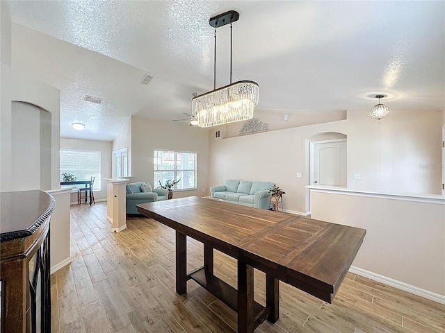 dining area featuring a textured ceiling, light hardwood / wood-style floors, vaulted ceiling, and ceiling fan