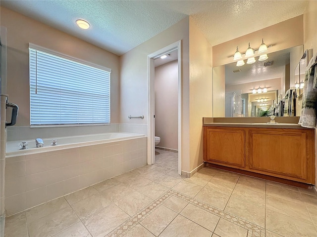 bathroom with vanity, a relaxing tiled tub, a textured ceiling, tile patterned floors, and toilet