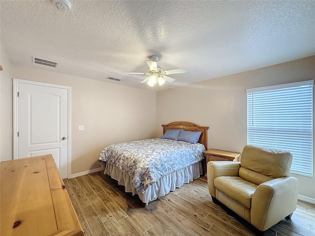 bedroom with ceiling fan, hardwood / wood-style flooring, and a textured ceiling