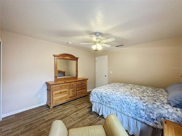 bedroom featuring ceiling fan, dark wood-type flooring, and a textured ceiling