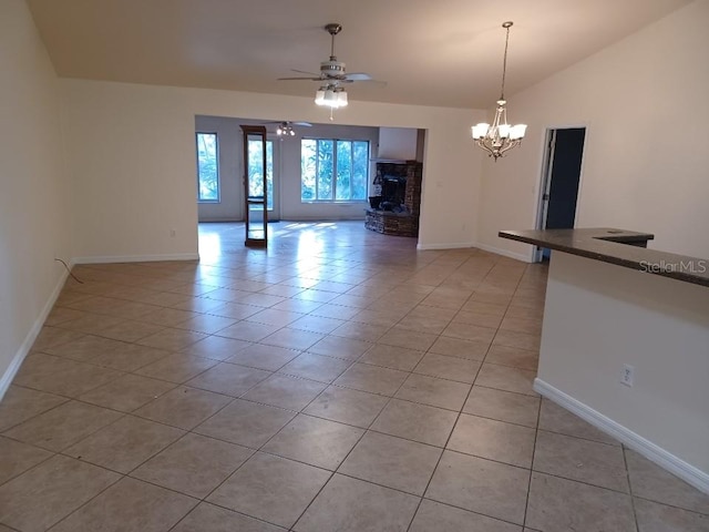 tiled spare room with ceiling fan with notable chandelier and lofted ceiling